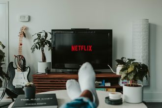 Pessoa sentada no sofá assistando a Netflix