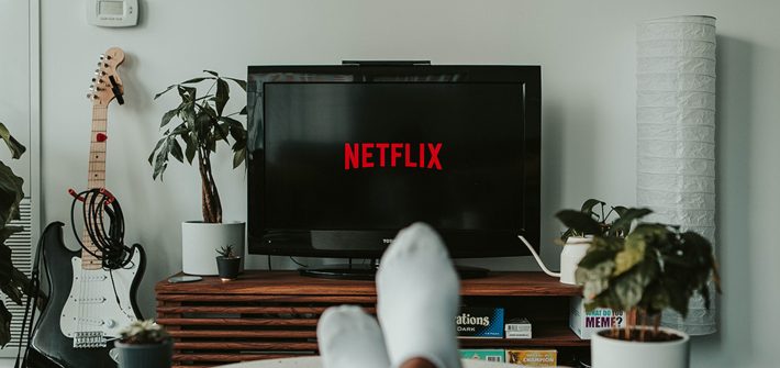 Pessoa sentada no sofá assistando a Netflix