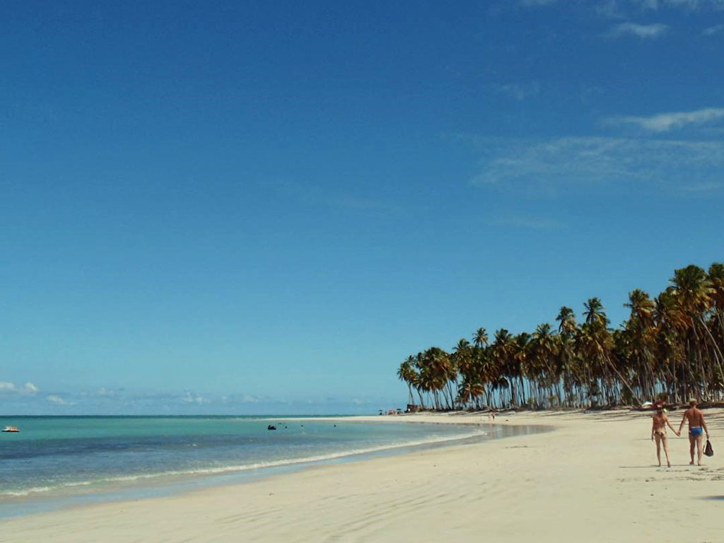 Casal caminhando pela areia na praia